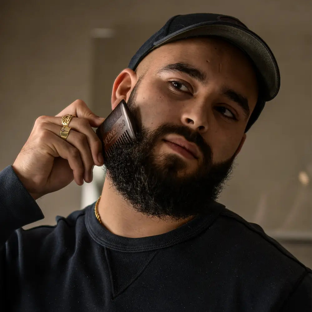 Een man met een lange baard die een baardkam gebruikt.
