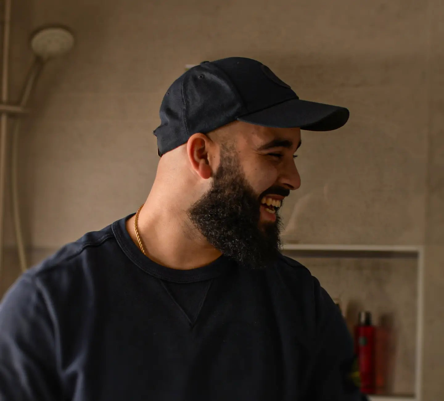 Een lachende man in een badkamer met een volle baard.